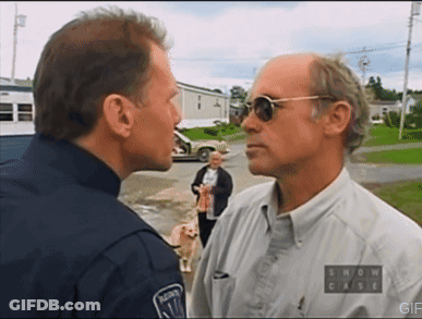 A Man Wearing Sunglasses And A Show Case Shirt Talks To A Police Officer GIF