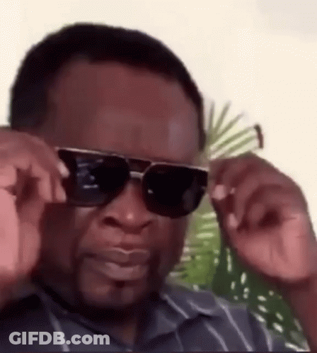 A Man Wearing Sunglasses And A Striped Shirt Is Adjusting His Sunglasses . GIF