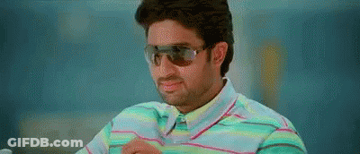 A Man Wearing Sunglasses And A Striped Shirt Is Sitting Down . GIF
