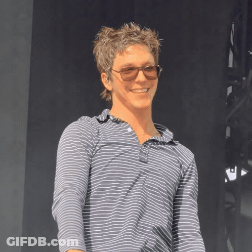 A Man Wearing Sunglasses And A Striped Shirt Smiles At The Camera GIF