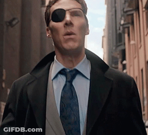 A Man Wearing Sunglasses And A Suit And Tie Is Walking Down A City Street . GIF