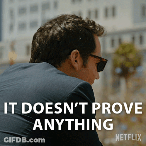 A Man Wearing Sunglasses And A Suit Has The Words " It Does N't Prove Anything " On His Back GIF