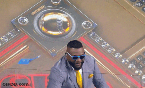 A Man Wearing Sunglasses And A Suit Holds Up A Large Omg Sign GIF