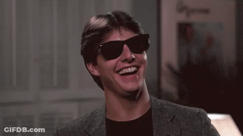 A Man Wearing Sunglasses And A Suit Is Laughing . GIF