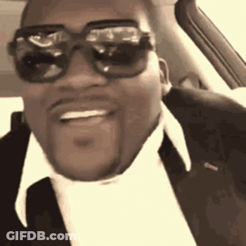 A Man Wearing Sunglasses And A Suit Is Sitting In A Car . GIF
