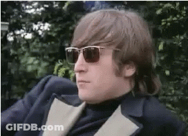 A Man Wearing Sunglasses And A Suit Is Sitting On A Chair . GIF