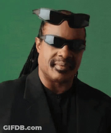 A Man Wearing Sunglasses And A Suit Is Smiling . GIF