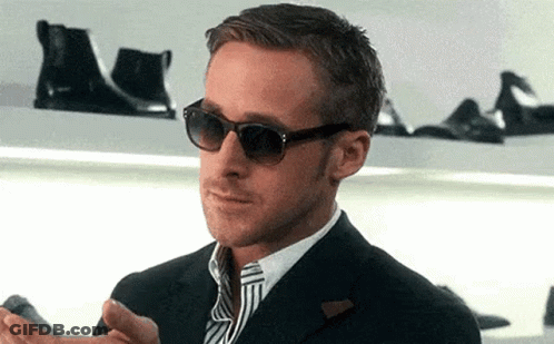 A Man Wearing Sunglasses And A Suit Is Standing In Front Of A Shelf With Shoes . GIF