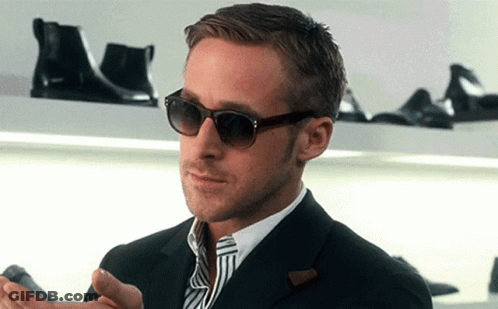 A Man Wearing Sunglasses And A Suit Is Standing In Front Of A Shoe Shelf GIF