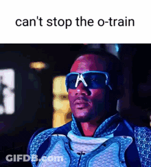 A Man Wearing Sunglasses And A Suit Is Standing In Front Of A Sign That Says Can 'T Stop The O-Train GIF