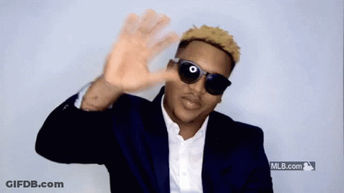 A Man Wearing Sunglasses And A Suit Is Waving His Hand GIF