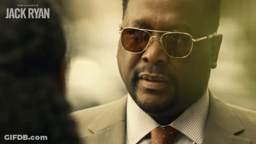 A Man Wearing Sunglasses And A Suit Talks To Another Man With The Name Jack Ryan On The Bottom GIF