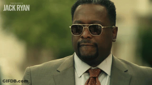 A Man Wearing Sunglasses And A Suit With The Name Jack Ryan On The Bottom Right GIF
