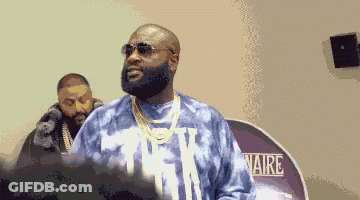 A Man Wearing Sunglasses And A Tie Dye Shirt Stands In Front Of A Sign That Says Aire . GIF