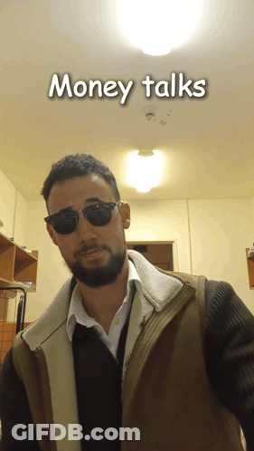 A Man Wearing Sunglasses And A Vest With The Words Money Talks Behind Him GIF