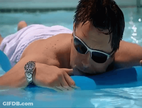 A Man Wearing Sunglasses And A Watch Is Laying In The Water GIF