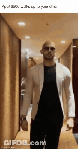 A Man Wearing Sunglasses And A White Jacket Walks Up To His Dms GIF