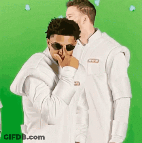 A Man Wearing Sunglasses And A White Jacket With A Nbc Logo GIF