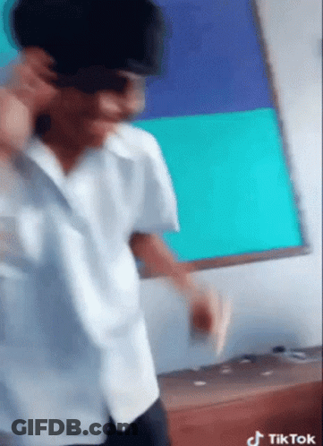 A Man Wearing Sunglasses And A White Shirt Is Dancing In Front Of A White Board That Says Tik Tok On It GIF