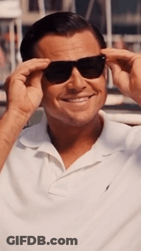 A Man Wearing Sunglasses And A White Shirt Smiles For The Camera GIF