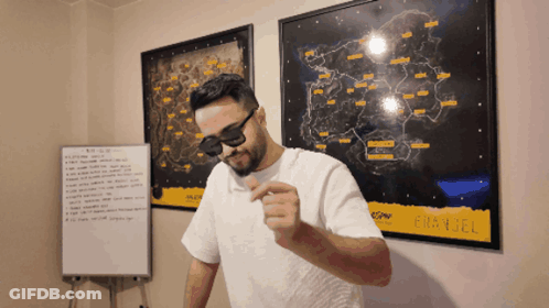A Man Wearing Sunglasses And A White Shirt Stands In Front Of A Map That Says ' Battlefield ' GIF