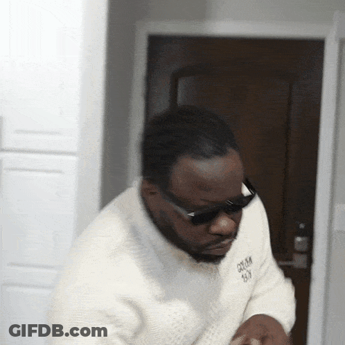 A Man Wearing Sunglasses And A White Sweater Has The Word Groom On The Front GIF