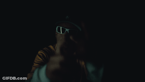 A Man Wearing Sunglasses And A Yellow Shirt With Bape On It GIF