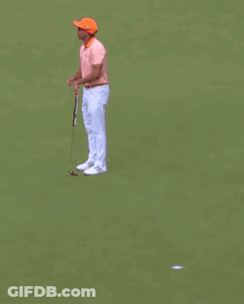 A Man Wearing Sunglasses And An Orange Hat Is Standing In Front Of A Crowd Holding A Golf Club . GIF