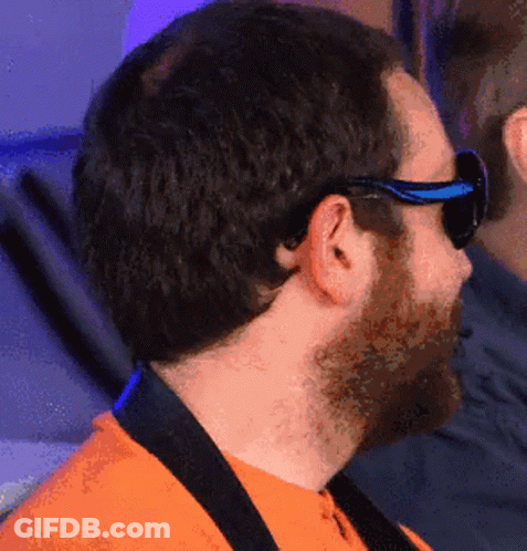 A Man Wearing Sunglasses And An Orange Shirt Looks To The Side GIF