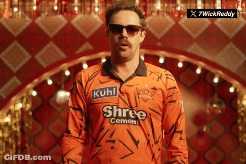 A Man Wearing Sunglasses And An Orange Shirt That Says Shree Cement On It GIF