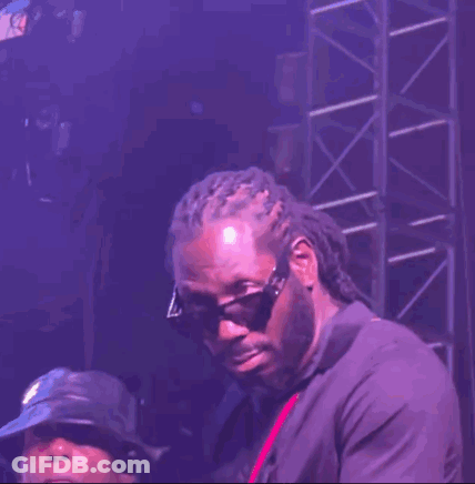 A Man Wearing Sunglasses And Dreadlocks Is Standing On A Stage GIF