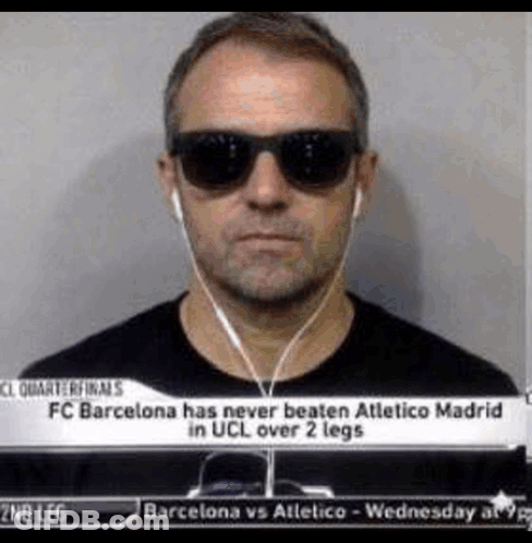 A Man Wearing Sunglasses And Ear Buds Is Standing In Front Of A Sign That Says Fc Barcelona GIF