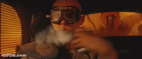 A Man Wearing Sunglasses And Goggles Is Smoking A Cigarette . GIF