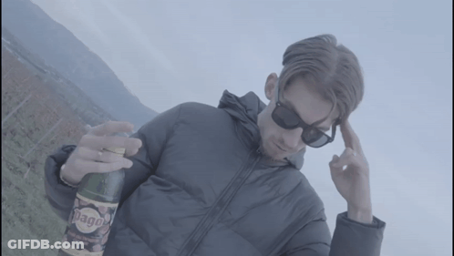 A Man Wearing Sunglasses Holds A Bottle Of Diago GIF