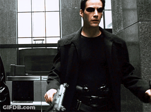 A Man Wearing Sunglasses Holds A Gun In His Hand GIF