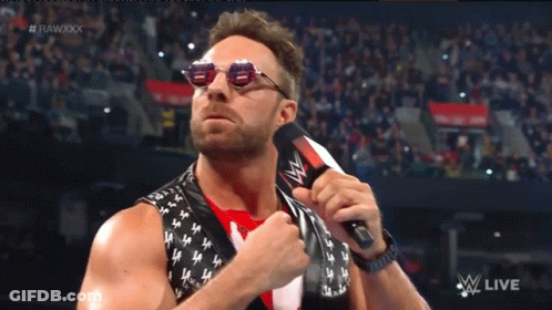A Man Wearing Sunglasses Holds A Microphone In Front Of A Crowd And The Words Rawxxx Are Visible GIF