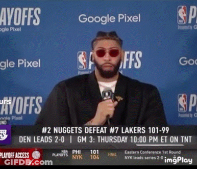 A Man Wearing Sunglasses Holds A Microphone In Front Of A Google Pixel Sign GIF