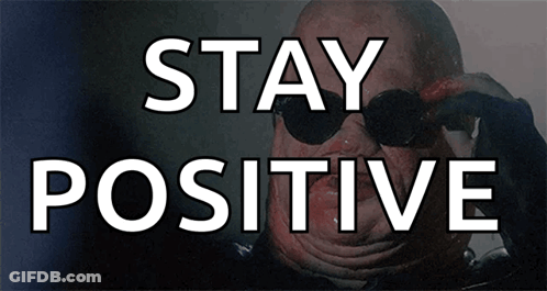 A Man Wearing Sunglasses Is Behind A Sign That Says " Stay Positive " GIF