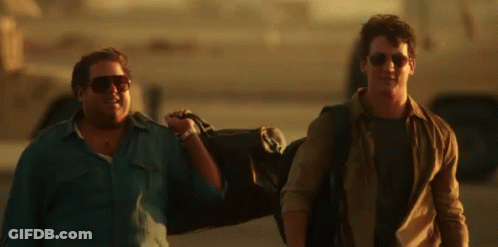 A Man Wearing Sunglasses Is Carrying A Duffel Bag GIF