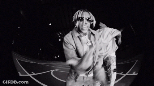 A Man Wearing Sunglasses Is Dancing On A Basketball Court . GIF