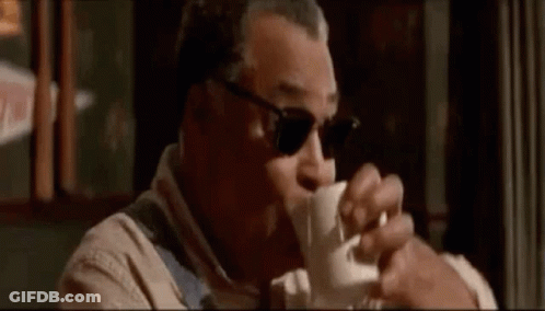 A Man Wearing Sunglasses Is Drinking A Cup Of Coffee In A Restaurant . GIF