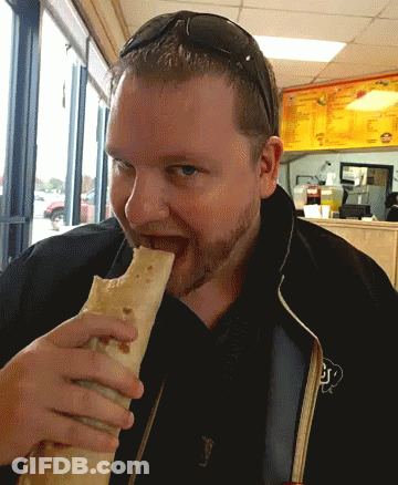 A Man Wearing Sunglasses Is Eating A Burrito With The Letter J On His Jacket GIF