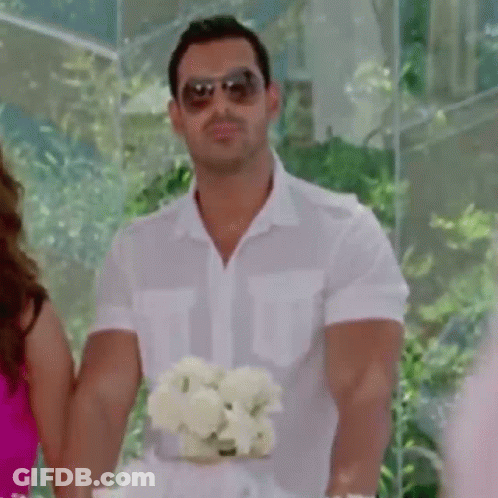 A Man Wearing Sunglasses Is Holding A Bouquet Of Flowers . GIF
