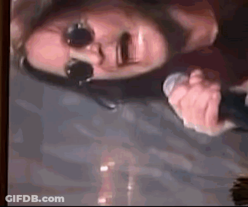 A Man Wearing Sunglasses Is Holding A Microphone In His Hand . GIF