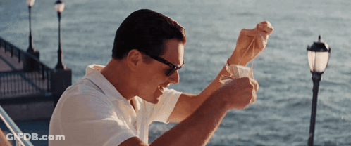 A Man Wearing Sunglasses Is Holding A Piece Of Paper In Front Of The Ocean GIF