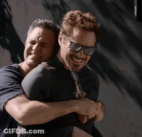 A Man Wearing Sunglasses Is Hugging Another Man Who Is Smiling GIF
