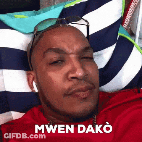 A Man Wearing Sunglasses Is Laying On A Striped Pillow . GIF
