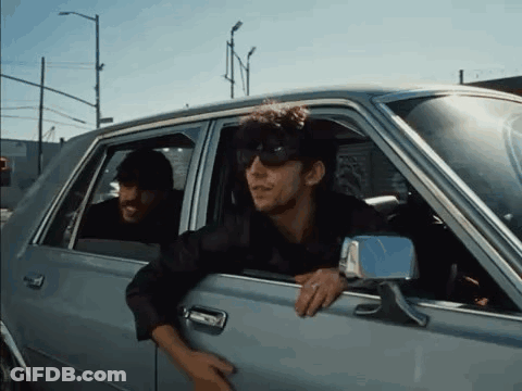 A Man Wearing Sunglasses Is Leaning Out Of A Car Window GIF