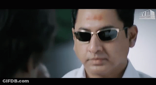 A Man Wearing Sunglasses Is Looking At Another Man 'S Face GIF