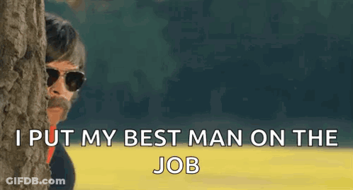 A Man Wearing Sunglasses Is Peeking Out From Behind A Tree . GIF